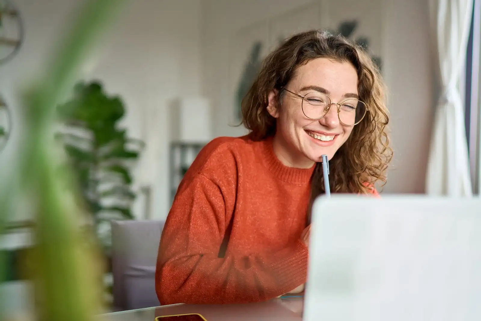 Mujer joven estudiando cursos de formación IA certificado desde casa con su ordenador portátil